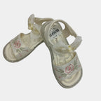 Pair of white sandals with floral designs on a light gray background