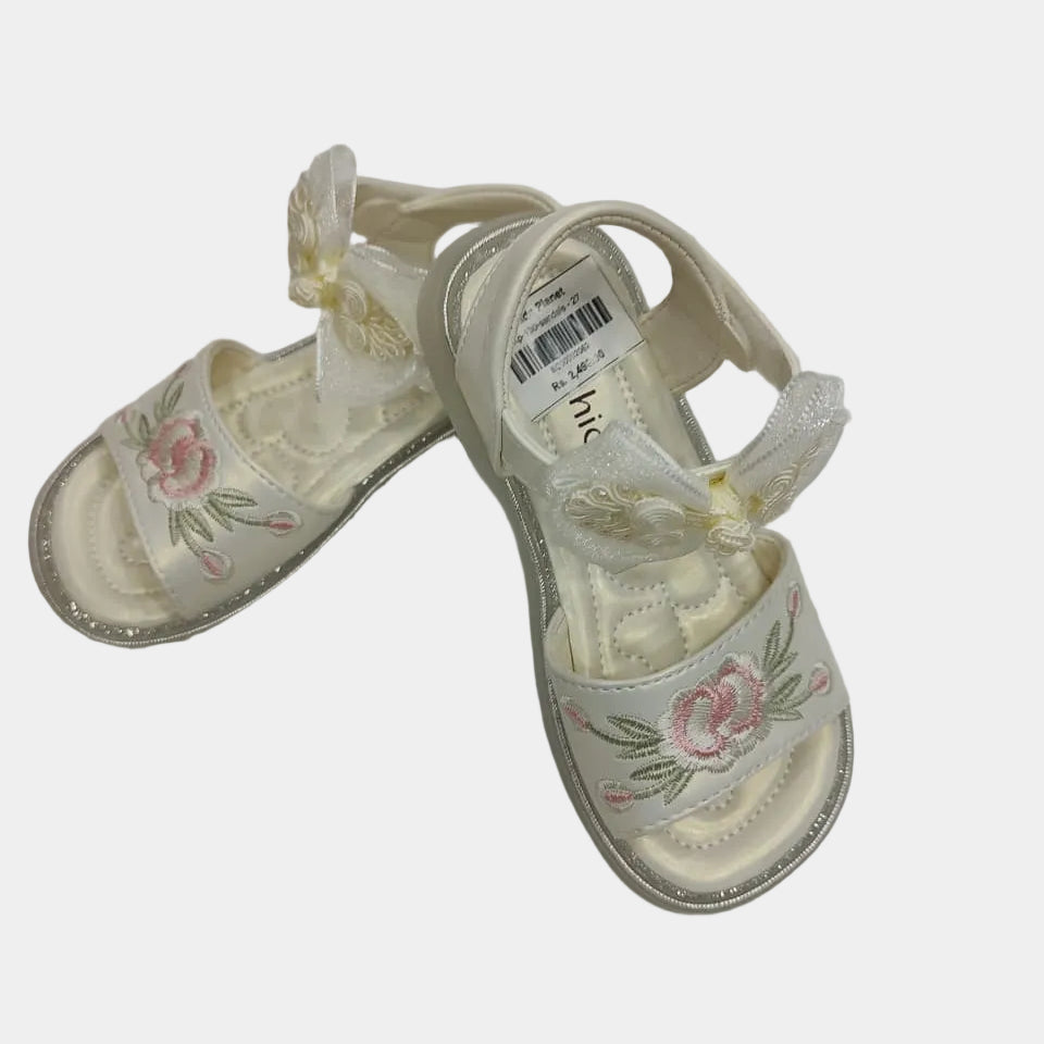Pair of white sandals with floral designs on a light gray background