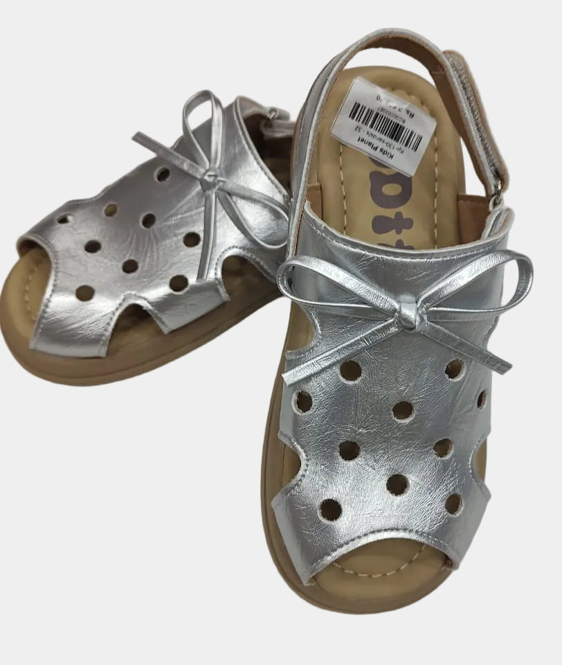 Silver sandals with brown soles on a light gray background