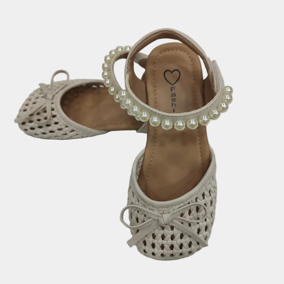 Beige sandals with pearl embellishments on a light gray background