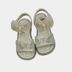 Pair of white sandals with floral designs on a light gray background