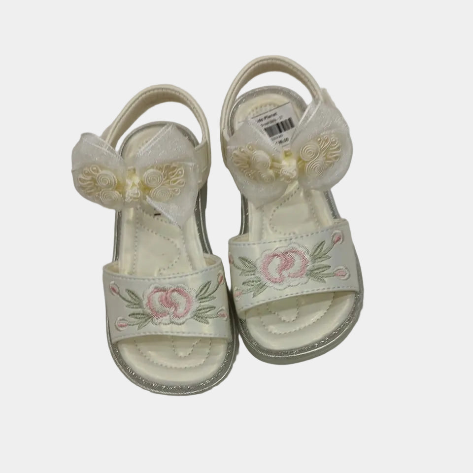 Pair of white sandals with floral designs on a light gray background