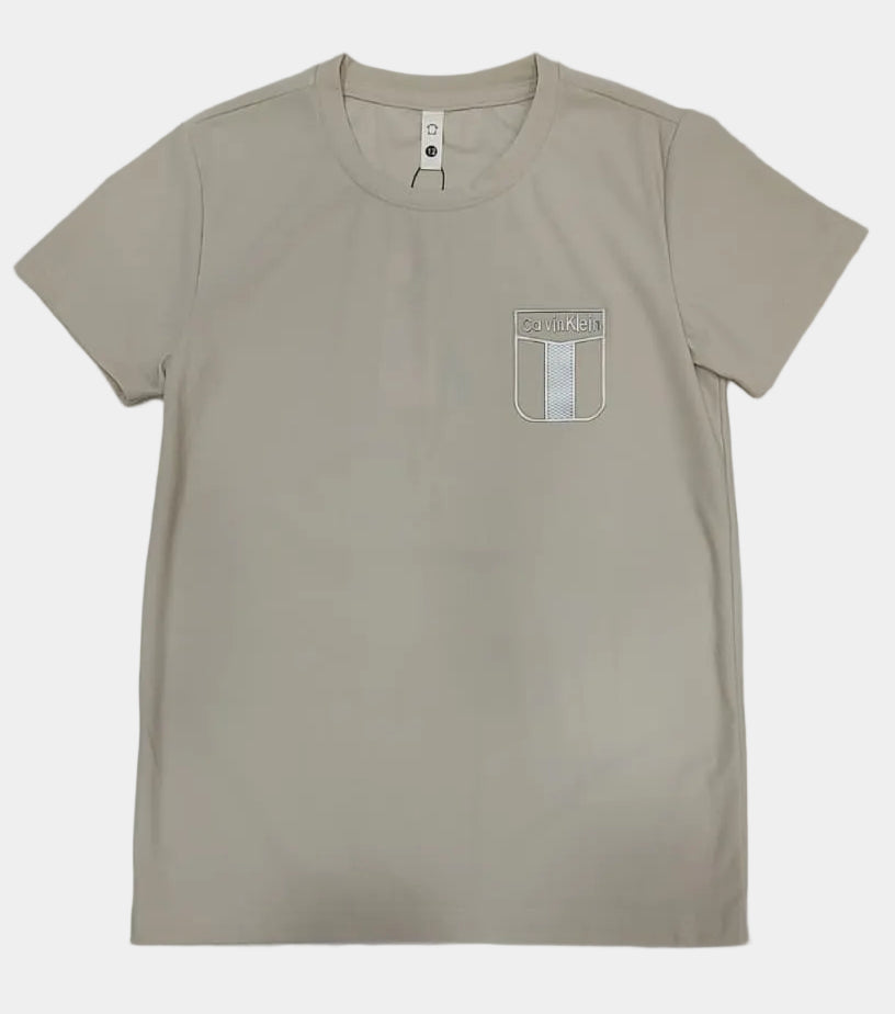 Beige t-shirt with a small logo on a light gray background