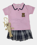 Pink dress with plaid skirt and teddy bear toy on a light gray background