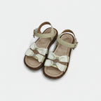 Pair of children's sandals with decorative bows on a light gray background