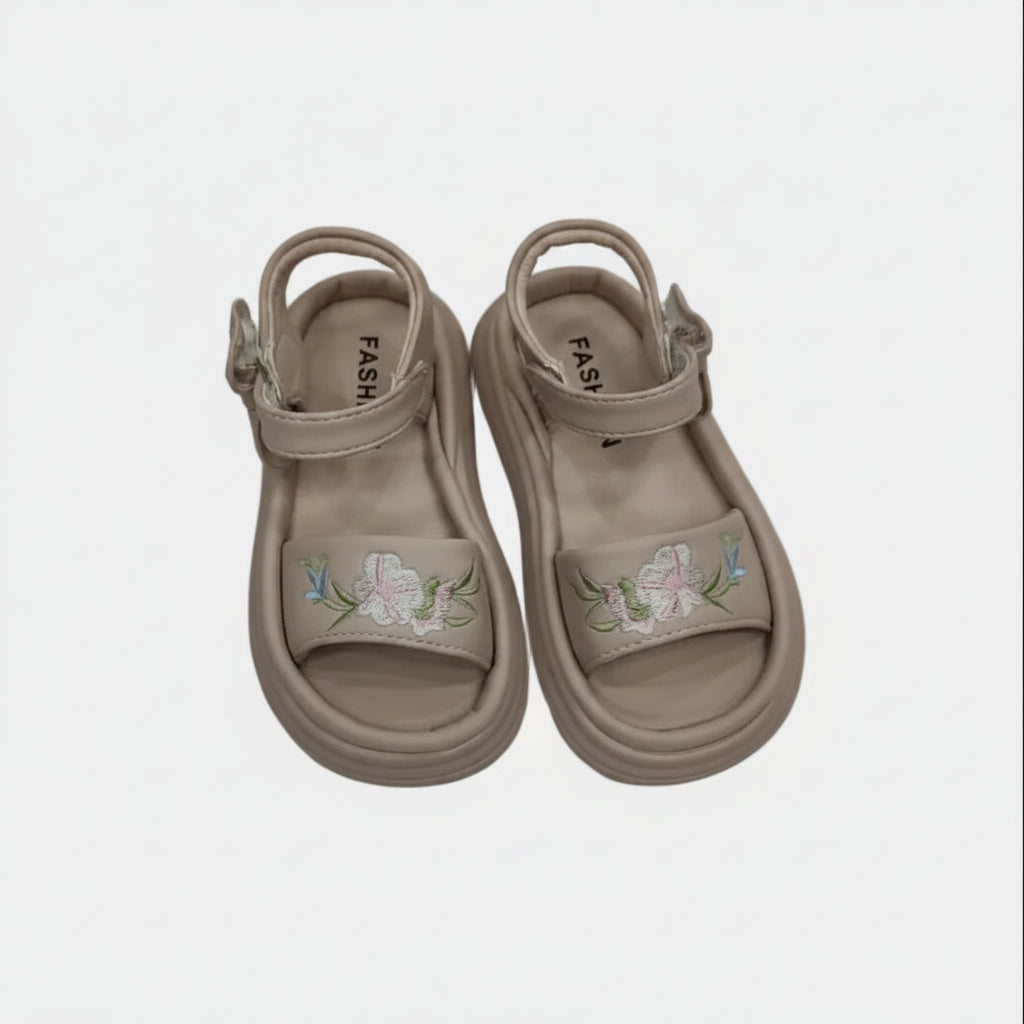 Pair of beige sandals with floral embroidery on a light gray background