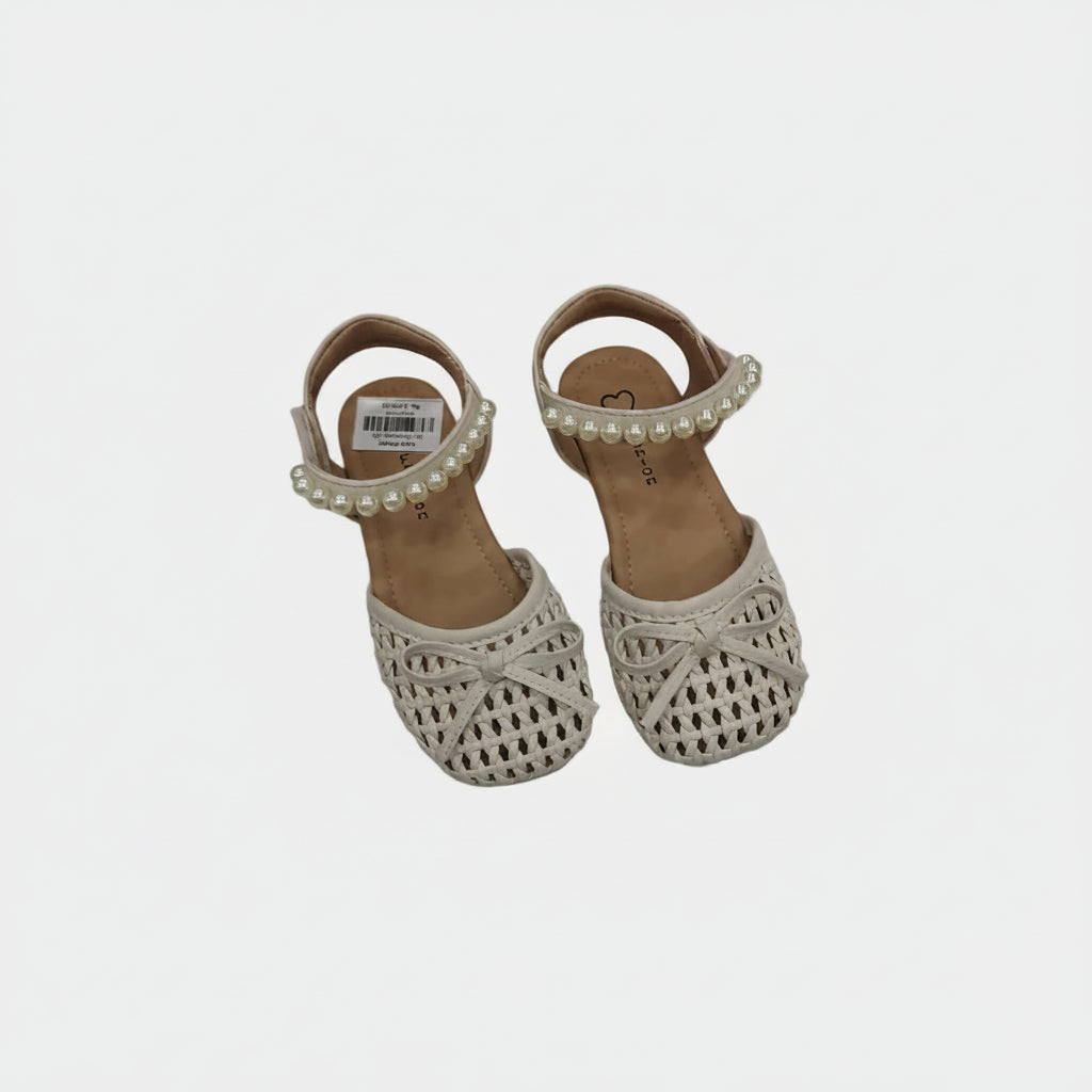 Pair of children's sandals with crochet detailing and pearl embellishments on a light gray background.