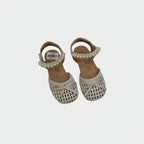 Pair of children's sandals with crochet detailing and pearl embellishments on a light gray background.