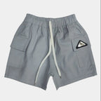 Gray shorts with a logo patch on a light gray background