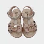 Pair of children's sandals with decorative bows on a light gray background