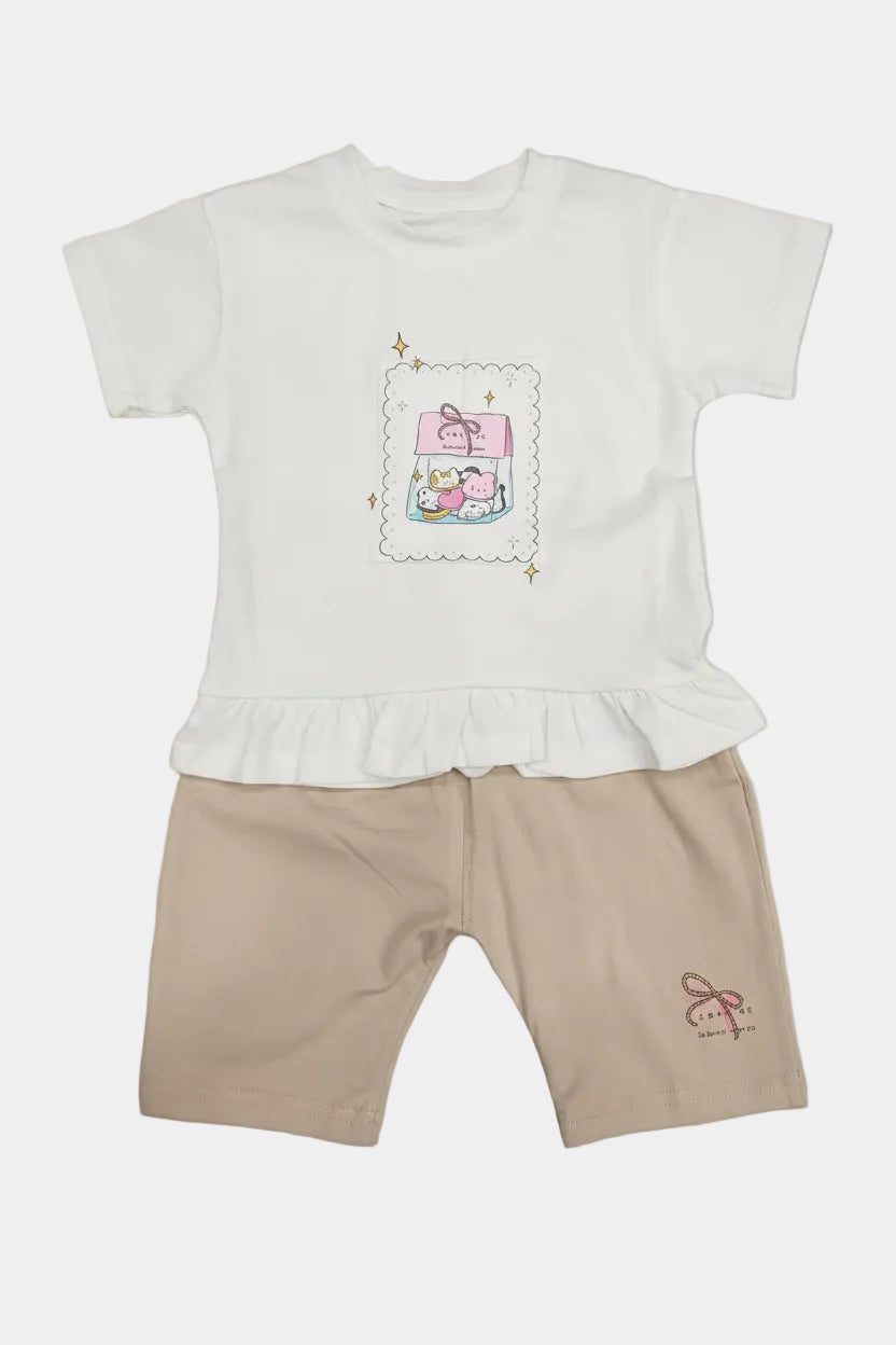 White ruffled top with cartoon design and beige shorts on a light gray background