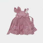 Pink children's dress with ruffles and bows on a light gray background