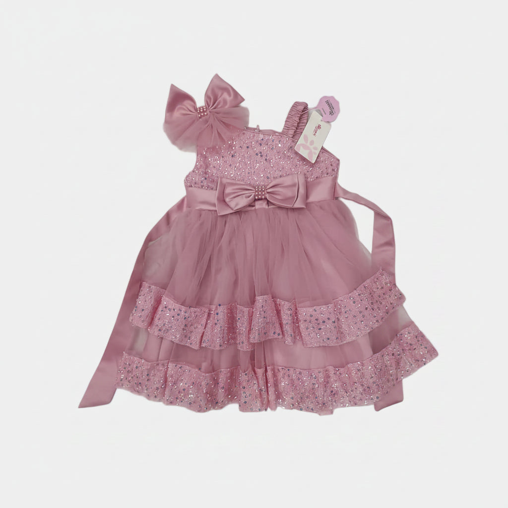 Pink children's dress with ruffles and bows on a light gray background