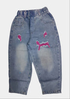 Distressed blue jeans with pink designs on a white background