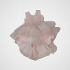 Pink baby dress with layers and embellishments on a white background