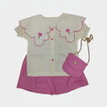 White top with pink floral designs and pink shorts