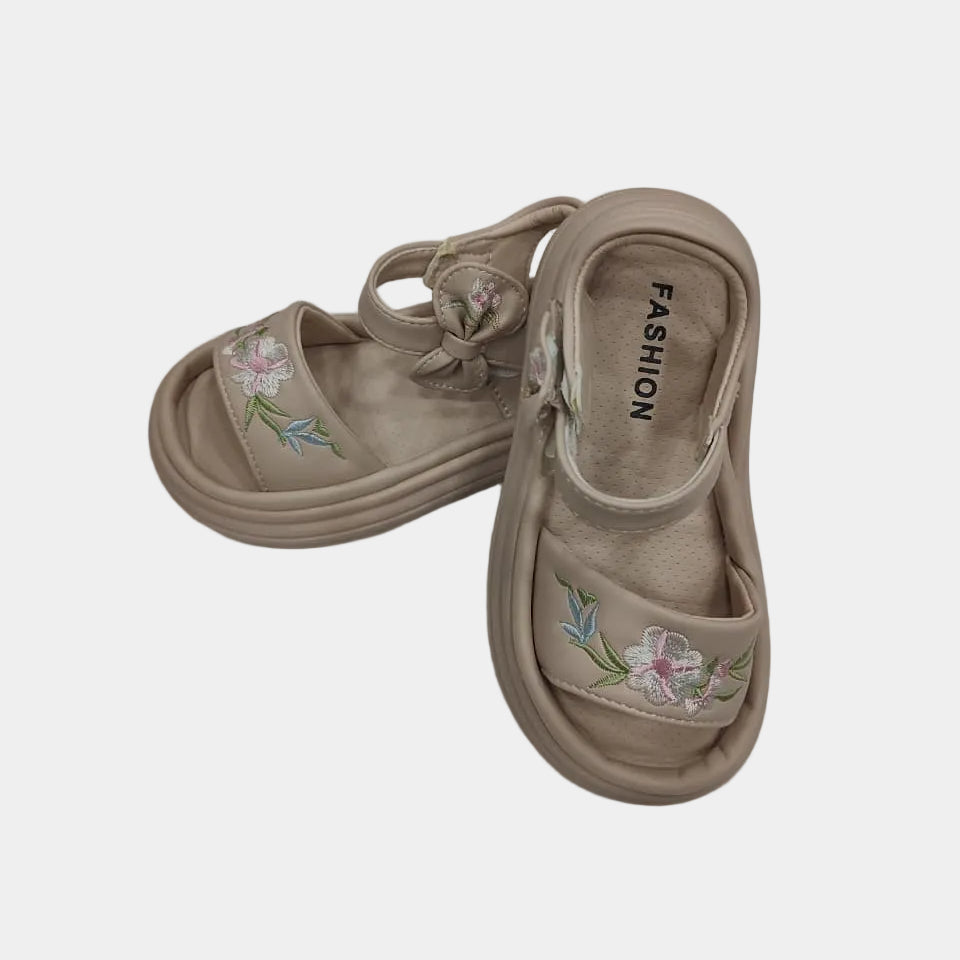 Pair of beige sandals with floral embroidery on a light gray background