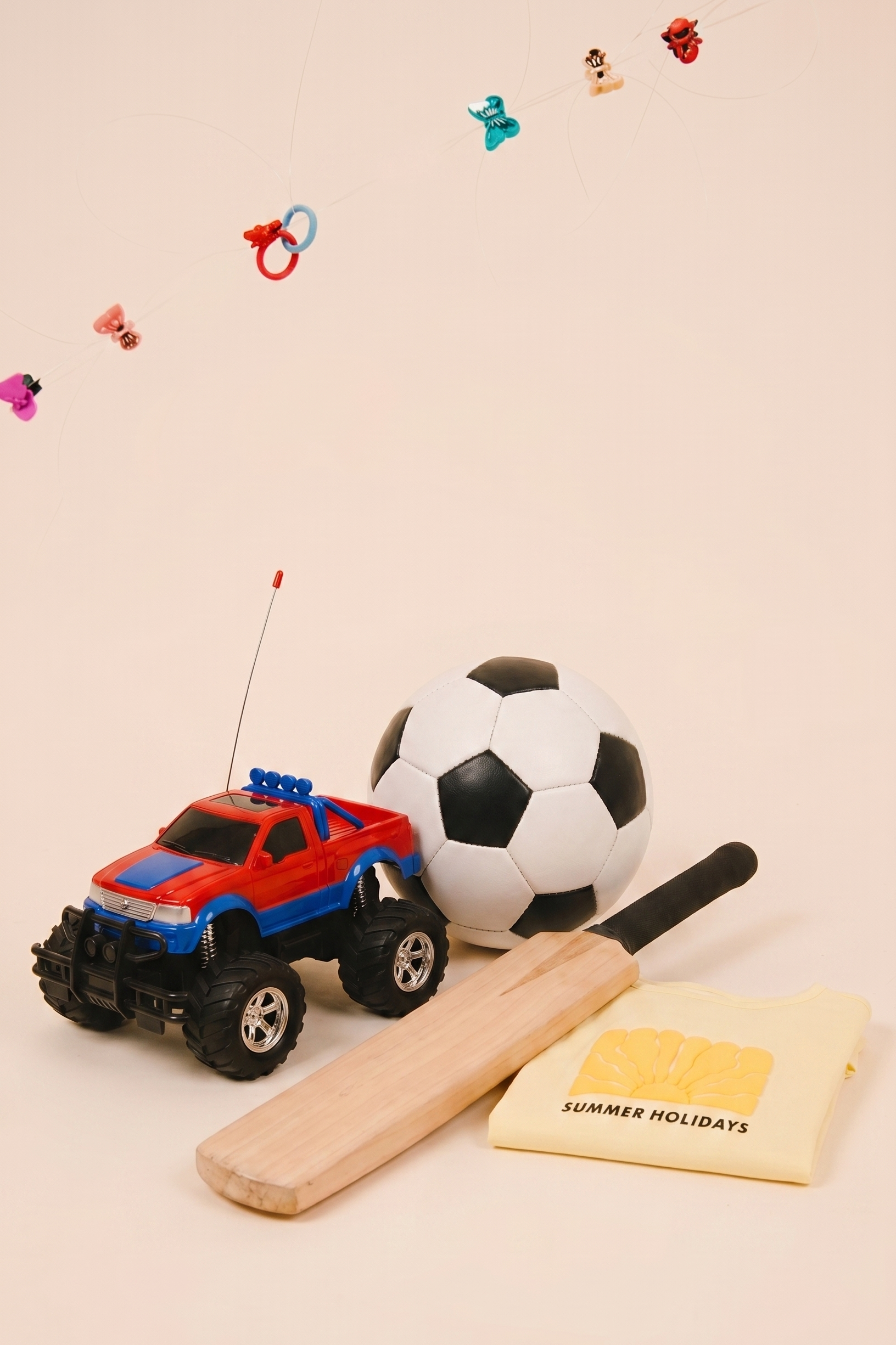 Toy car, soccer ball, bat, and 'Summer Holidays' towel on a beige background