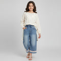 Pair of blue jeans with lace trim on a light gray background