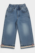 Pair of blue jeans with embroidered cuffs on a white background