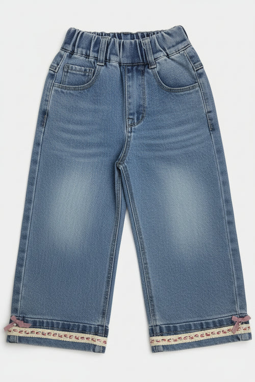 Pair of blue jeans with embroidered cuffs on a white background