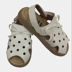 Pair of white sandals with brown soles on a white background